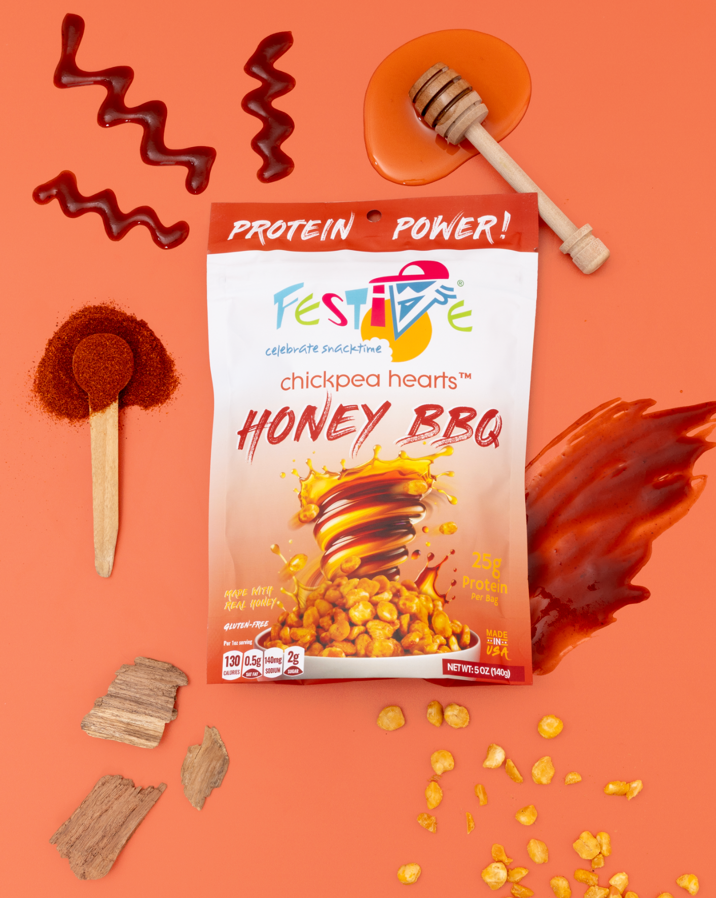 Packaging of Festive Chickpea Hearts Honey BBQ on an orange background with honey and spices.