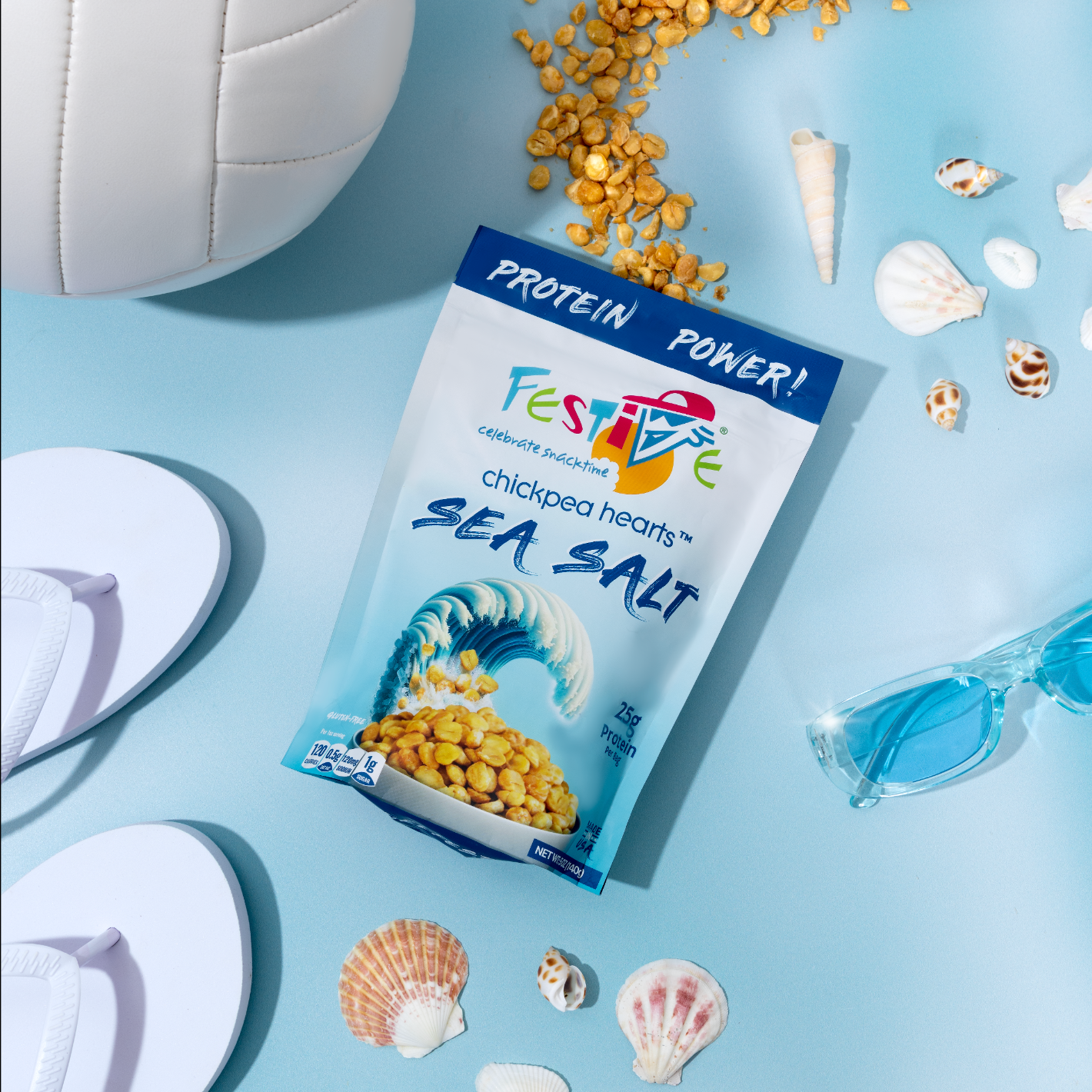 Festive chickpea hearts sea salt packaging on a blue background with seashells and sunglasses.